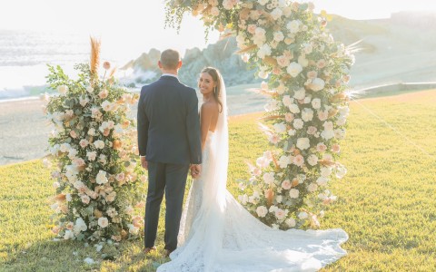 a man and woman standing under a floral arch