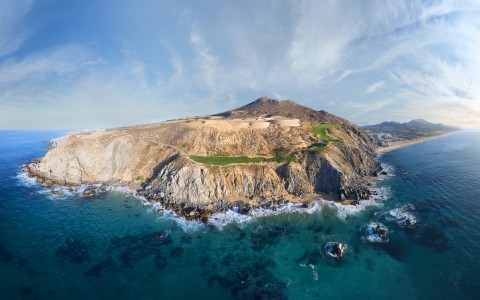 an aerial view of a rocky island with a beach and a body of water