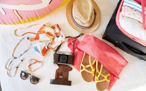 a beach bag with sunglasses and a swimsuit and a hat