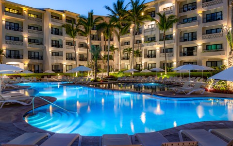 a pool with palm trees and a building with lights