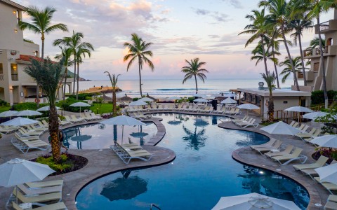 a pool with umbrellas and chairs and palm trees