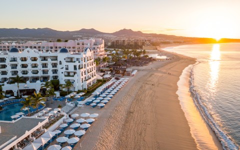 a beach with a large building and umbrellas