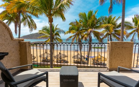 a deck with chairs and a table overlooking a beach
