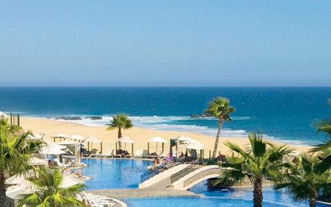 a swimming pool with umbrellas and palm trees on a beach