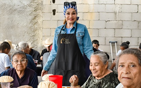 a woman standing in front of a table with people around
