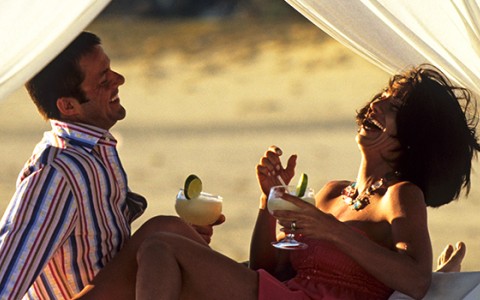 a man and woman laughing while holding drinks
