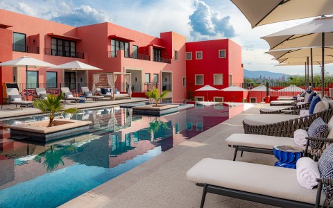 a pool with chairs and umbrellas in front of a red building
