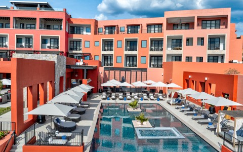 a pool with umbrellas and chairs in front of a building