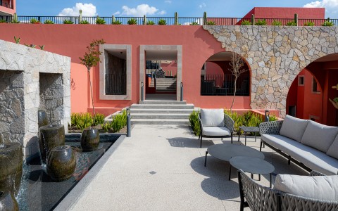 a patio with chairs and a fountain in front of a building