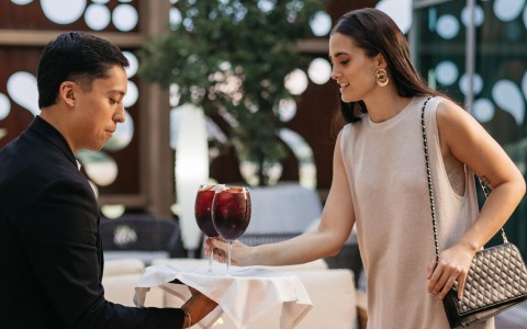 a man and woman holding a tray of wine glasses