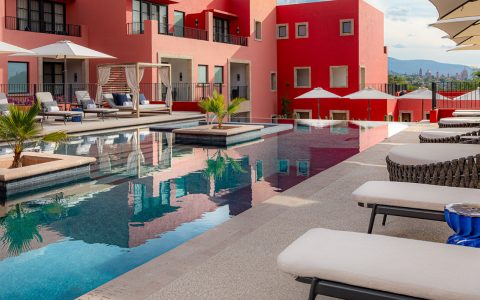 a pool with chairs and umbrellas in front of a red building