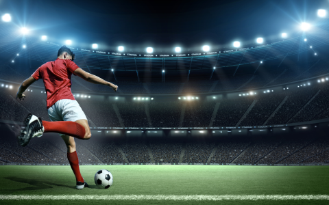 a football player kicking a football ball in a stadium
