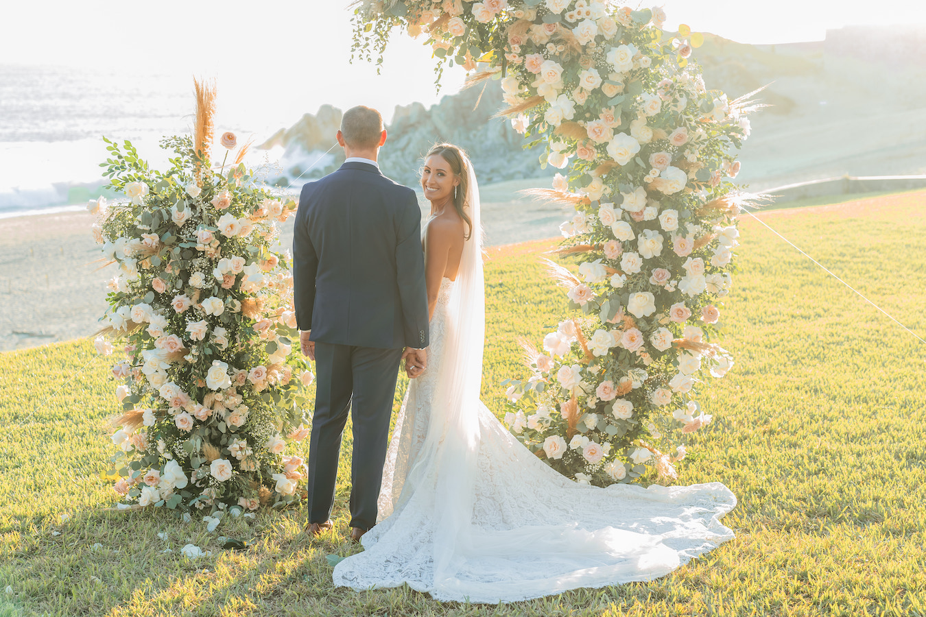 a man and woman standing under a floral arch