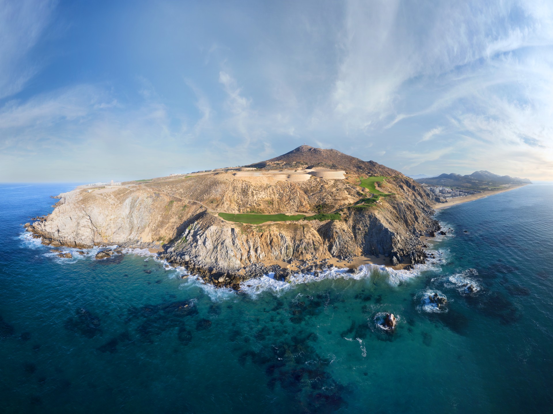 an aerial view of a rocky island with a beach and a body of water