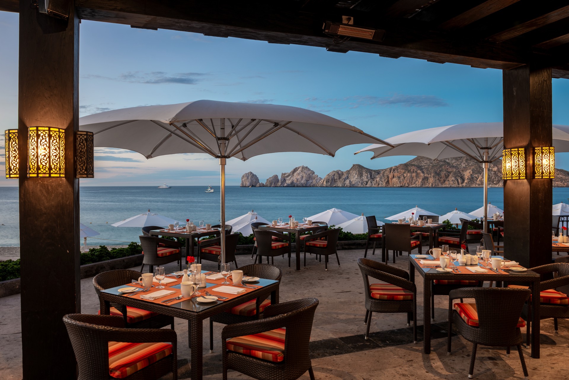 a restaurant with tables and umbrellas by the water
