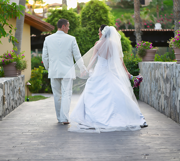 a man and woman in white wedding dress walking down a walkway