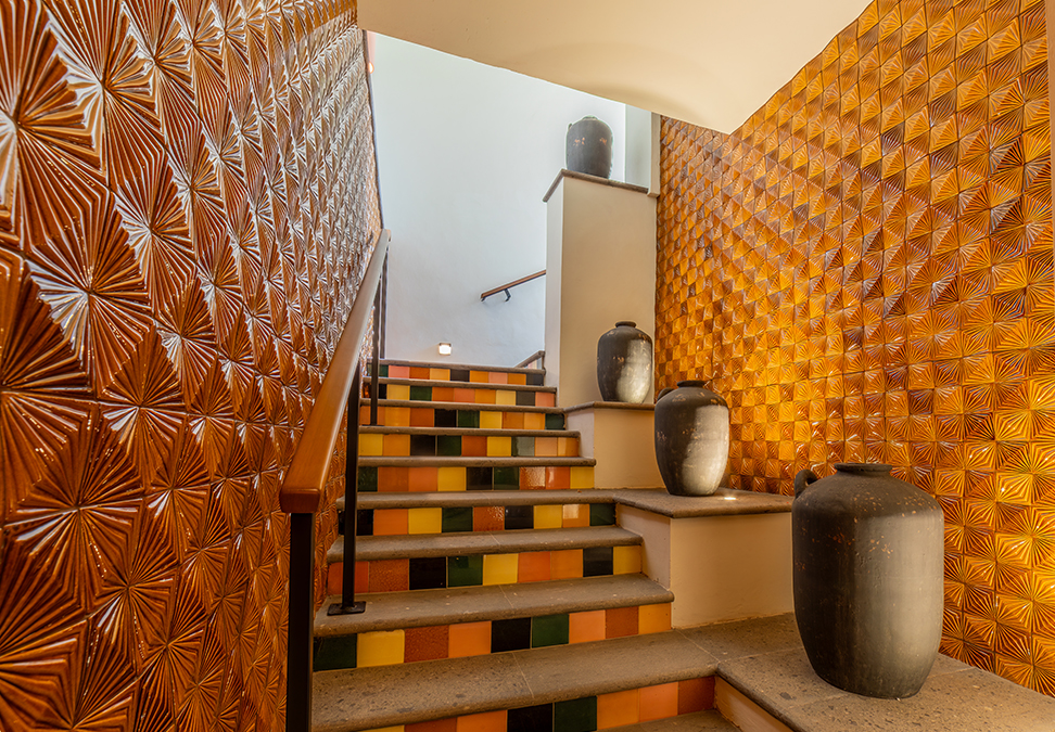 a staircase with a tile wall and a vase on the top