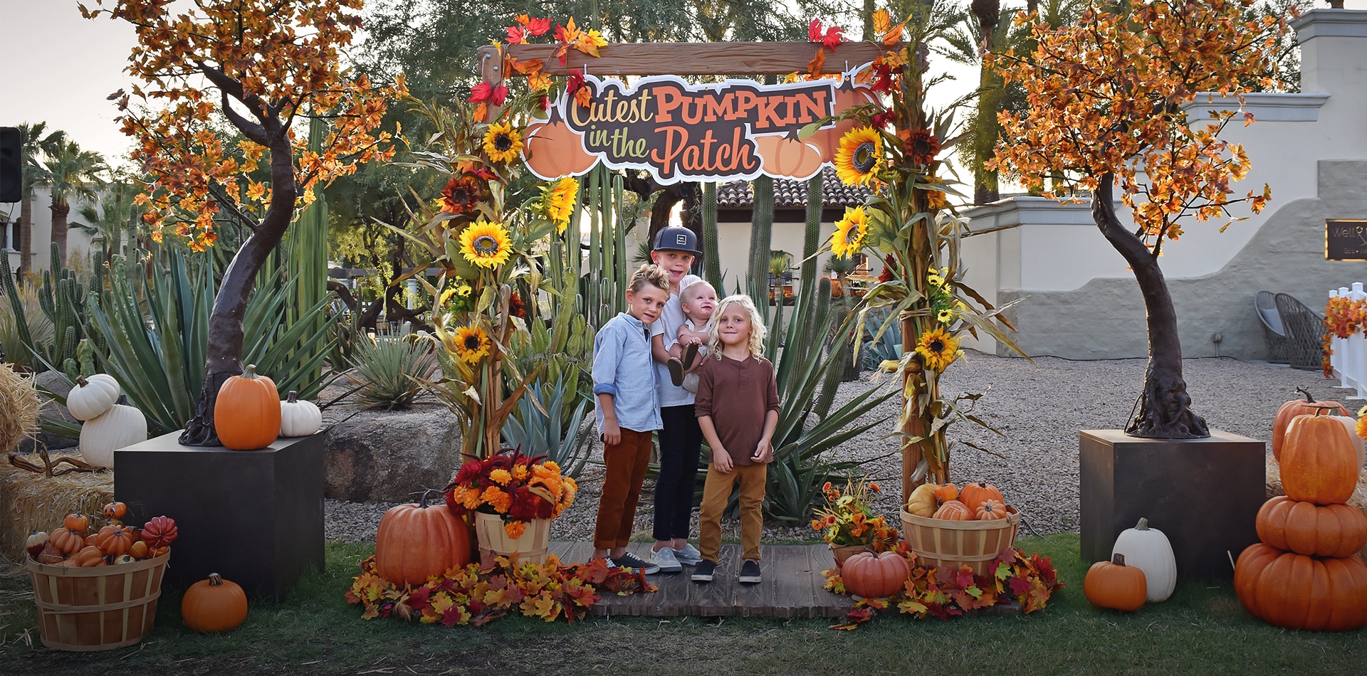 a group of kids standing under a pumpkin arch