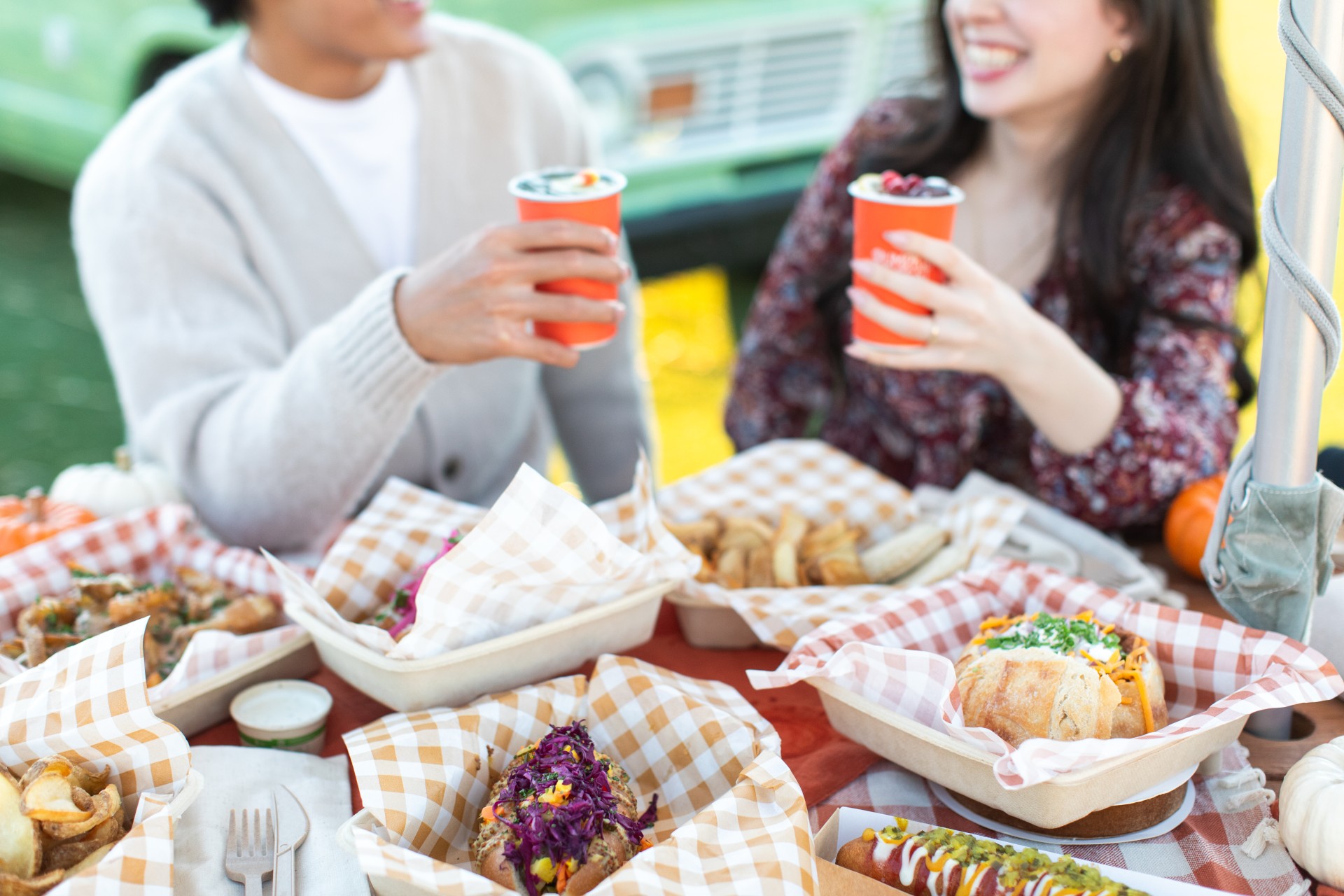a man and woman holding drinks and sitting at a table with food