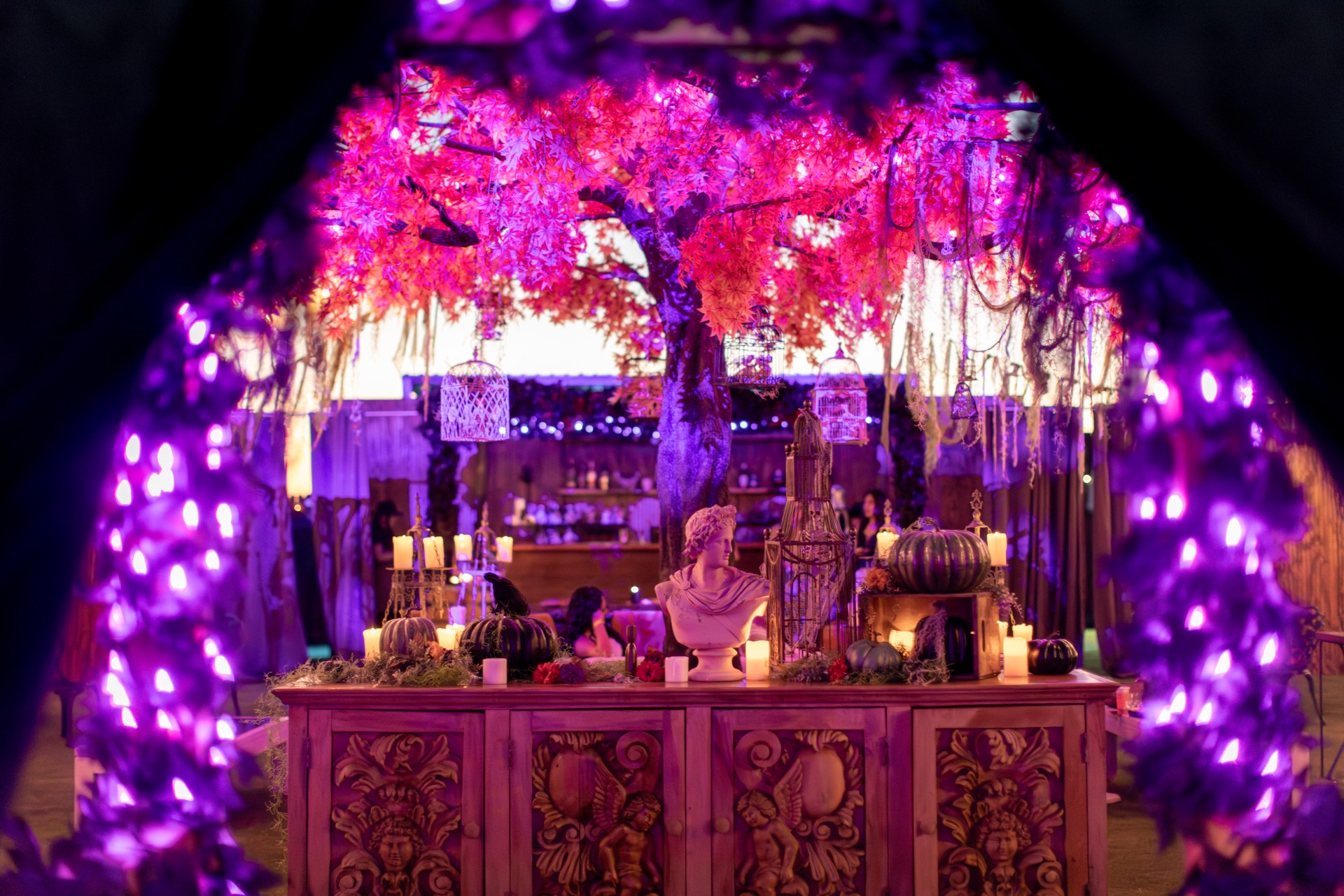 a table with candles and a statue under a tree