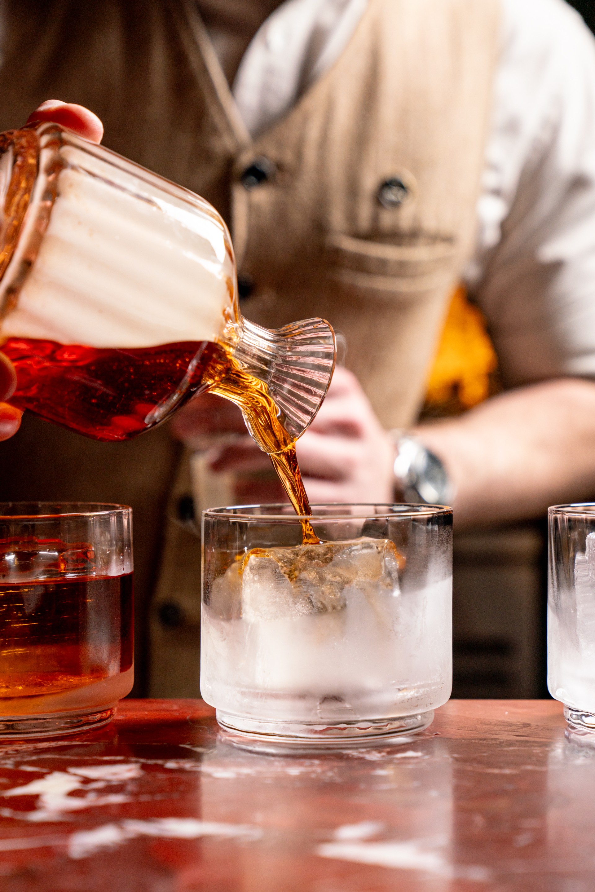 a person pouring a drink into a glass