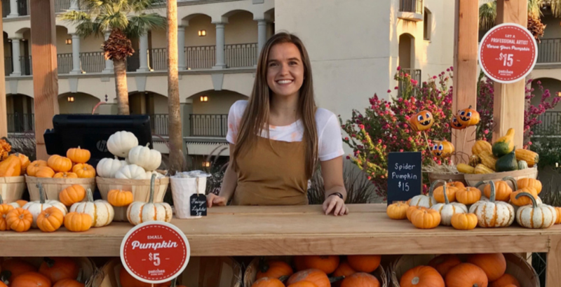a woman standing behind a counter with pumpkins