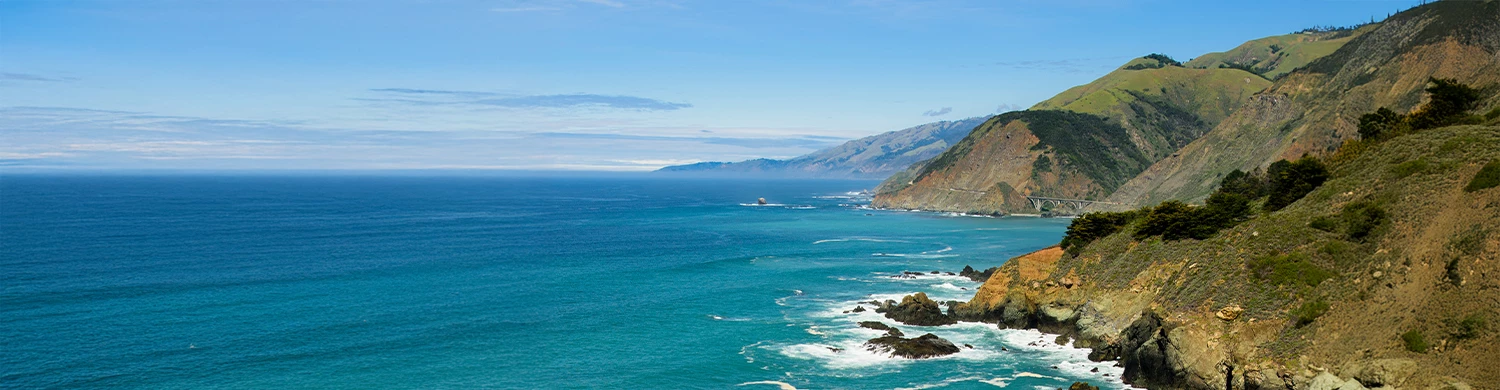 a body of water with rocks and mountains in the background
