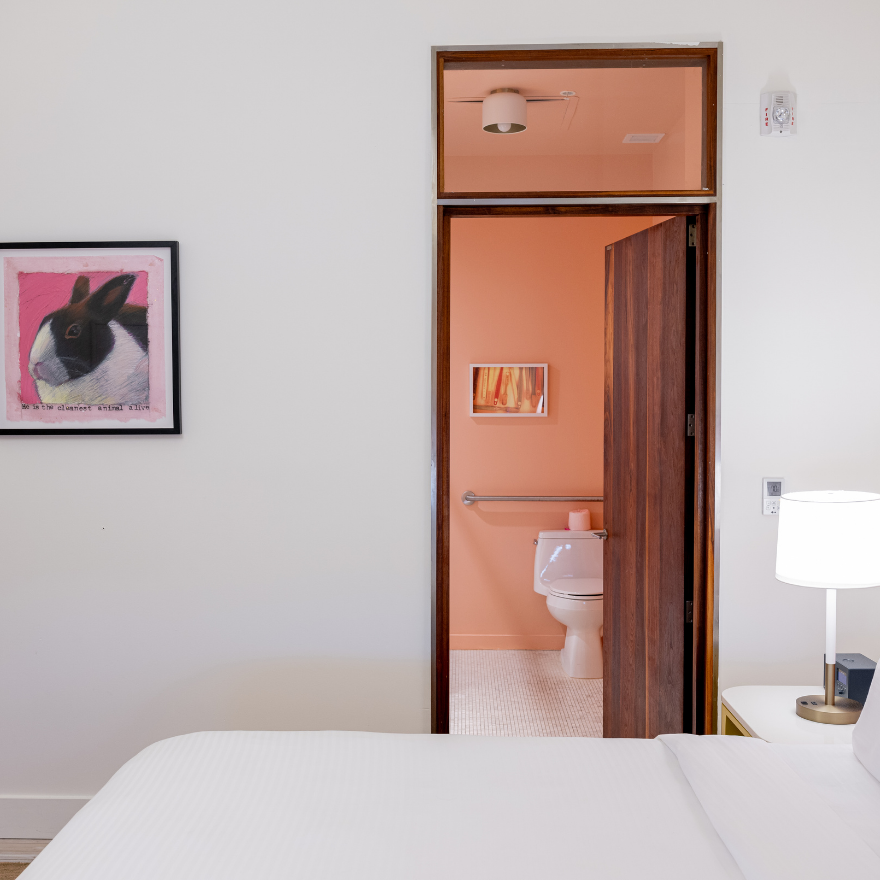 a bedroom with a white bed and a pink toilet