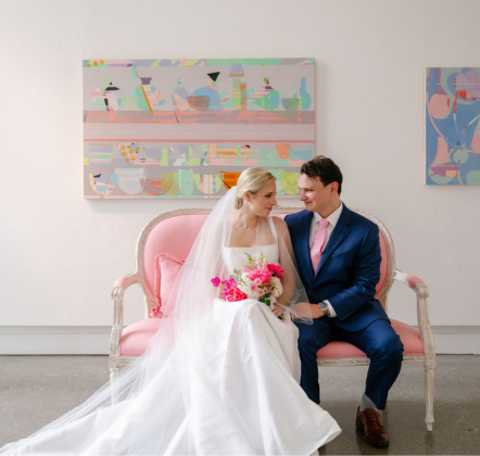 a man and woman sitting on a pink couch