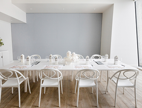 Closeup of a large white table and white chairs around it