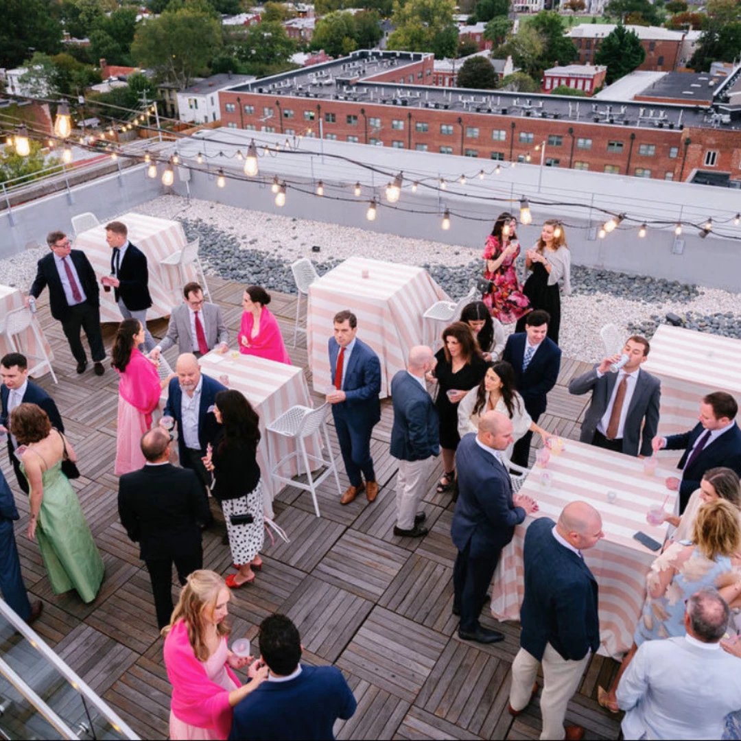 a group of people standing around tables on a rooftop