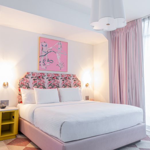 a bed with a pink floral headboard and a yellow nightstand