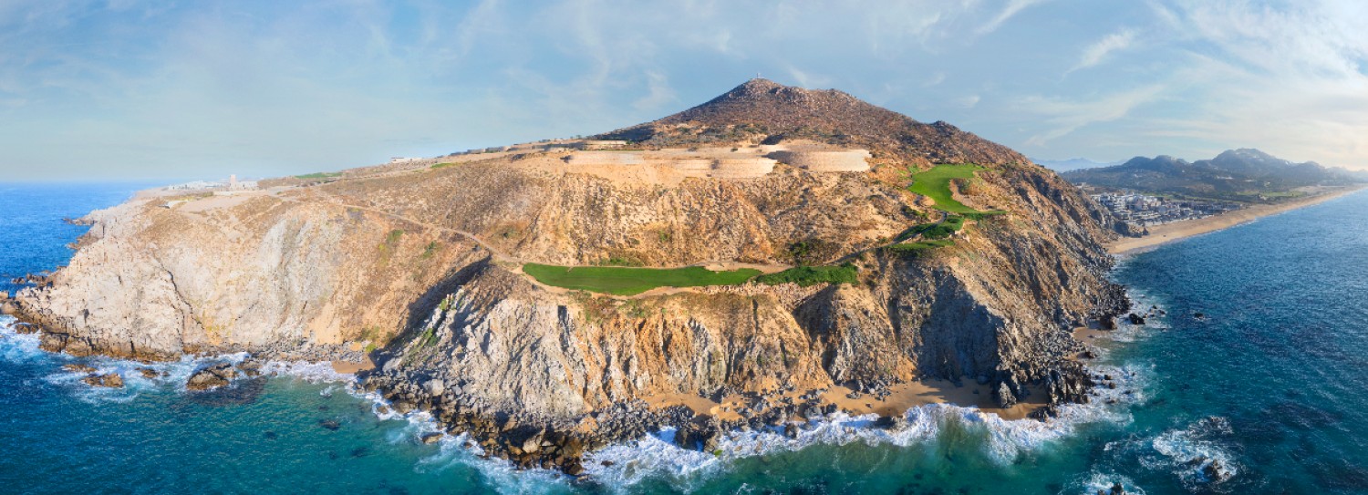 an aerial view of a rocky island with a beach and a body of water