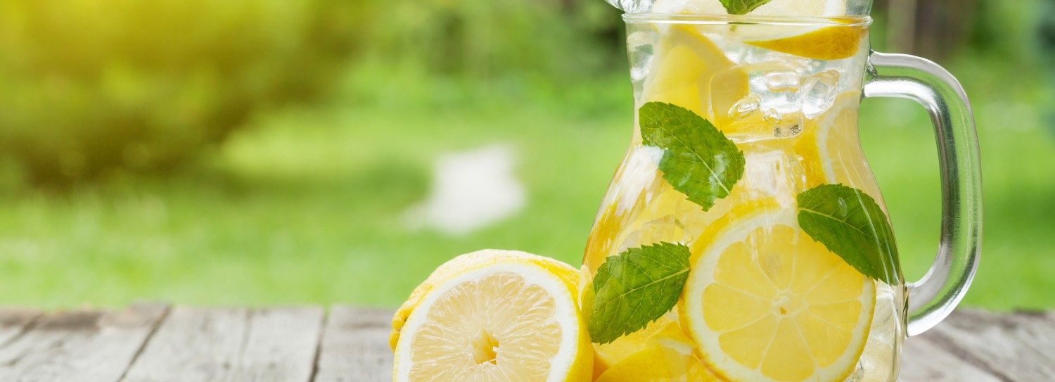 a pitcher of lemonade with lemons and mint leaves