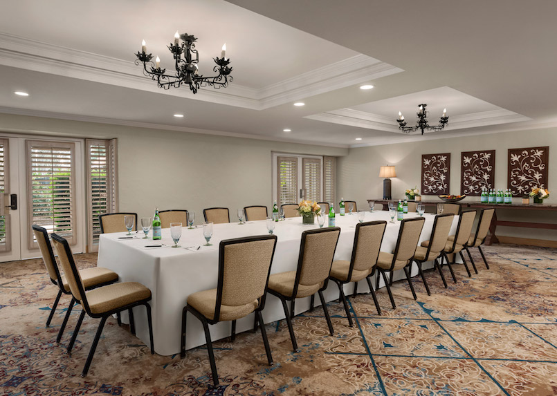 a large white table with wine glasses and chairs in a room