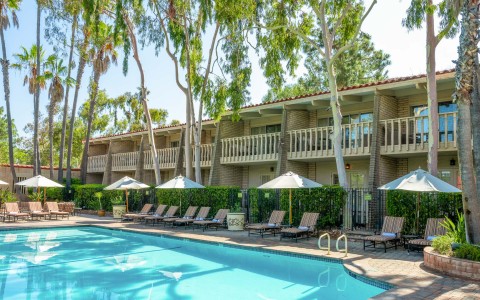 a pool with umbrellas and chairs in front of a building