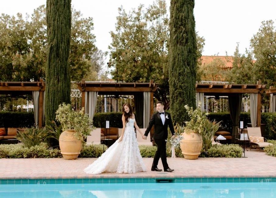 a man and woman in wedding attire standing by a pool
