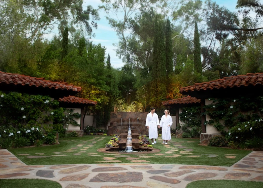 two women in white robes in a courtyard with a fountain