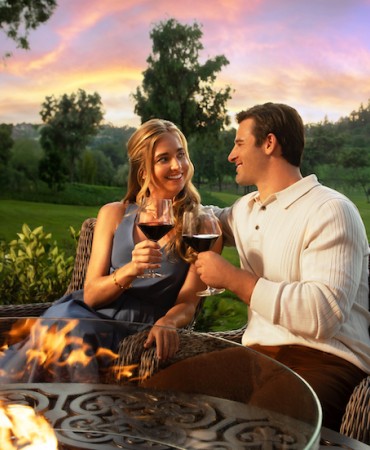 a man and woman sitting at a table with a glass of wine