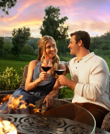 a man and woman sitting at a table with a glass of wine