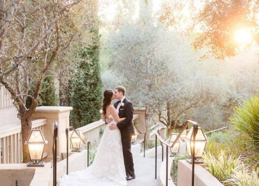 a man and woman kissing on a bridge with trees and lights