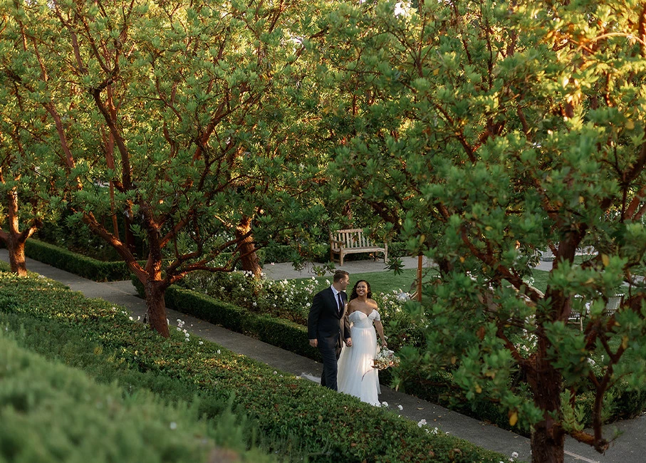 a man and woman in wedding attire walking down a path with trees