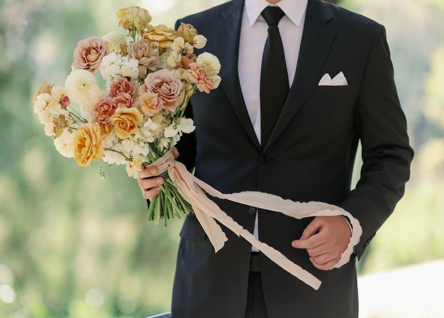 a man in a suit holding a bouquet of flowers