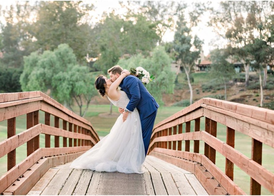 a man and woman kissing on a bridge