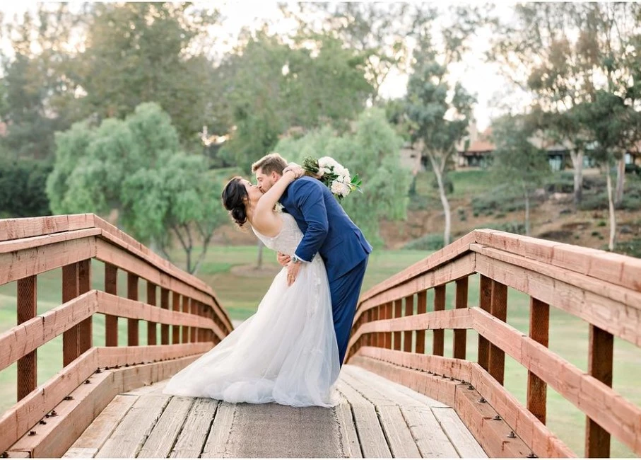 a man and woman kissing on a bridge