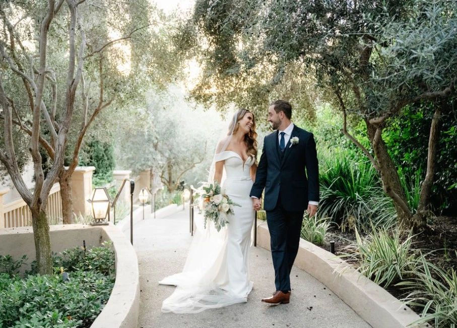a man and woman walking down a path with trees and plants