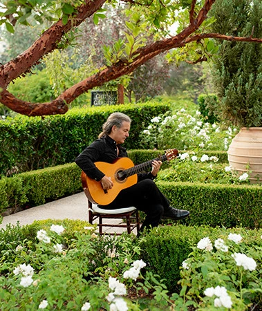 a man sitting on a chair playing a guitar