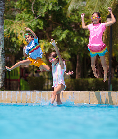 a group of children jumping into a pool
