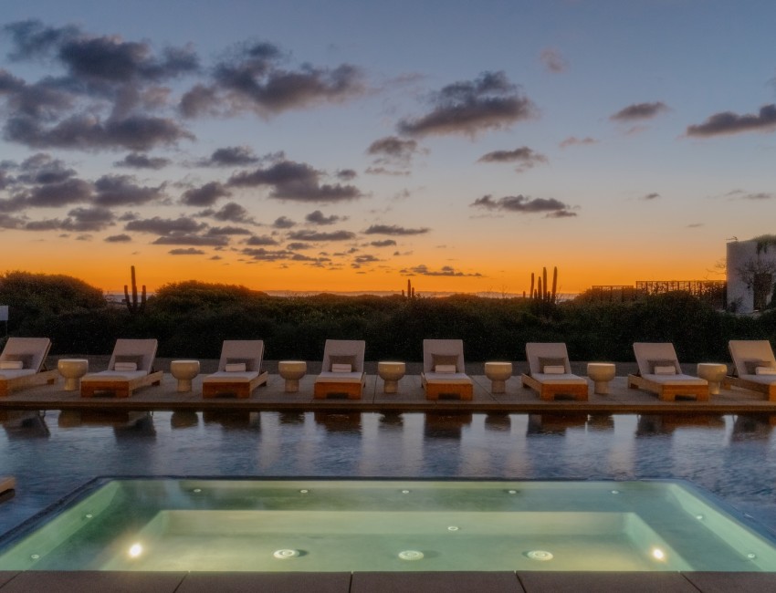 a pool with chairs and a sunset