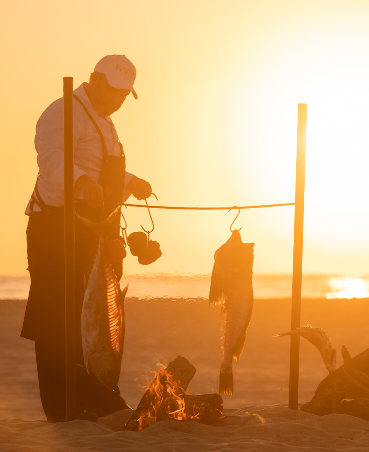 a man holding a fish from a fire